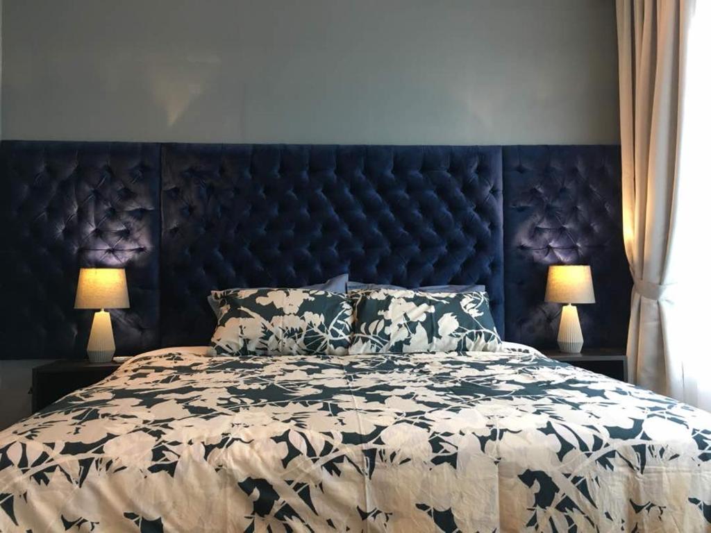 怡保Palm Suite Ipoh Octagon的一张大床,配有黑色床头板和两盏灯