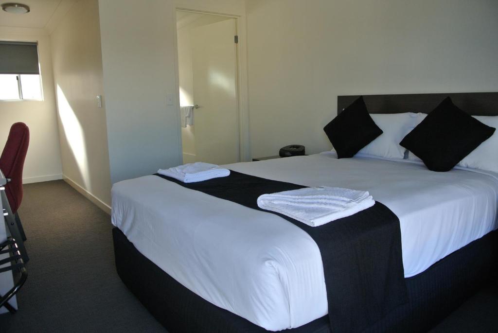 SpringsureDooley's Tavern & Motel Springsure的一间卧室配有一张大床,配有白色床单和黑色枕头。
