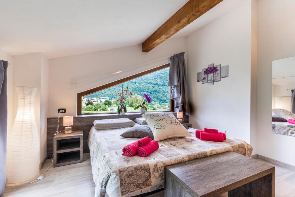 PiatedaB&B Valtellina Mon Amour的一间卧室设有大窗户和一张带红色枕头的床