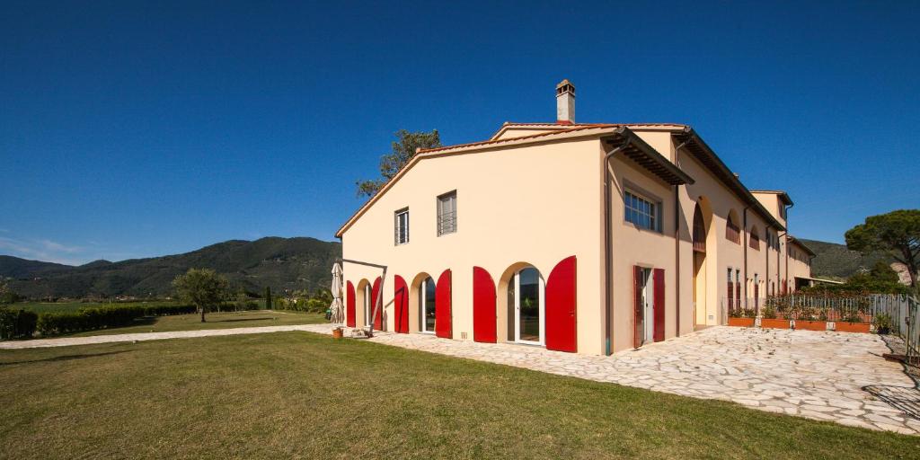 圣朱利亚诺-泰尔梅Cascina Canova B&B的一座白色和红色的大建筑,有草地庭院