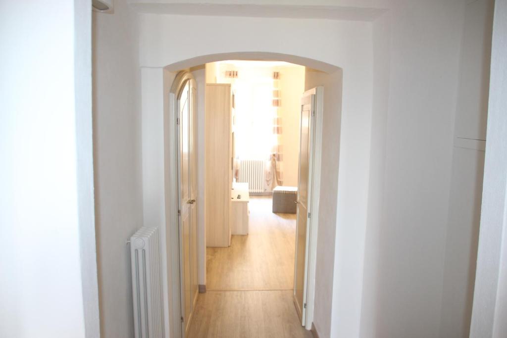 拉波拉诺泰尔梅Carolina Apartment的一条带白色墙壁和木地板的走廊和一个带门的走廊