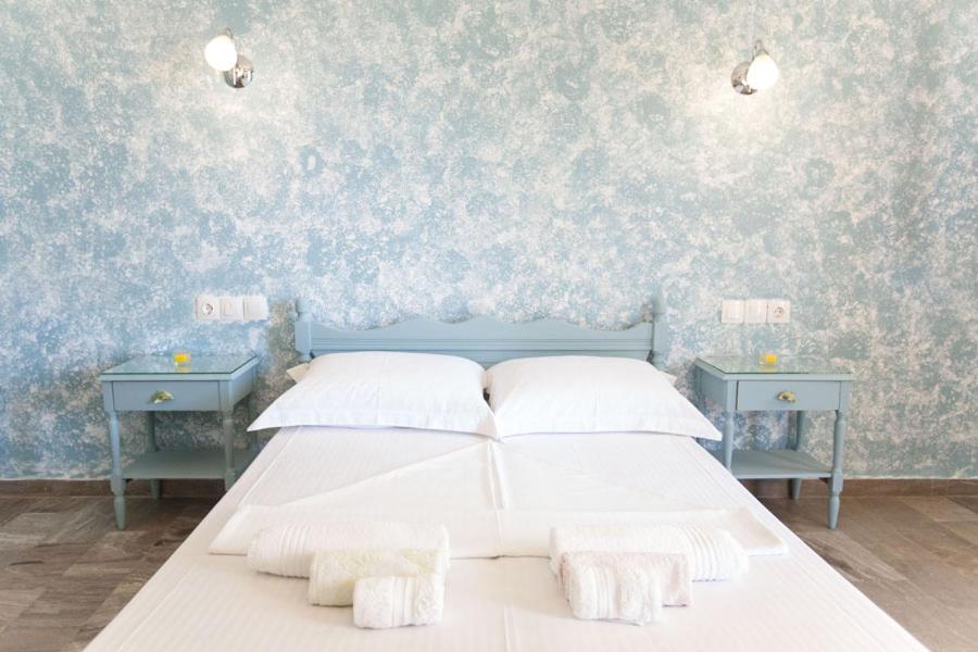 利瓦迪奥kyma studios的一间卧室配有白色的床和两张蓝色的桌子