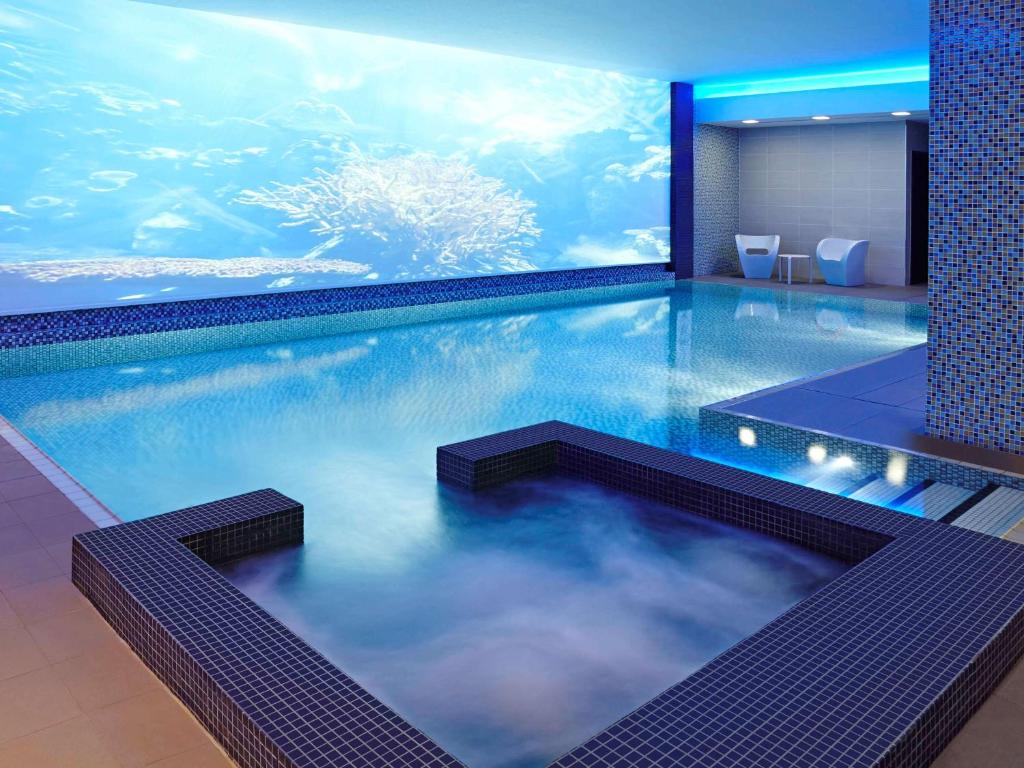 伦敦伦敦黑修士诺富特酒店的一个带水族馆的游泳池,位于酒店客房内