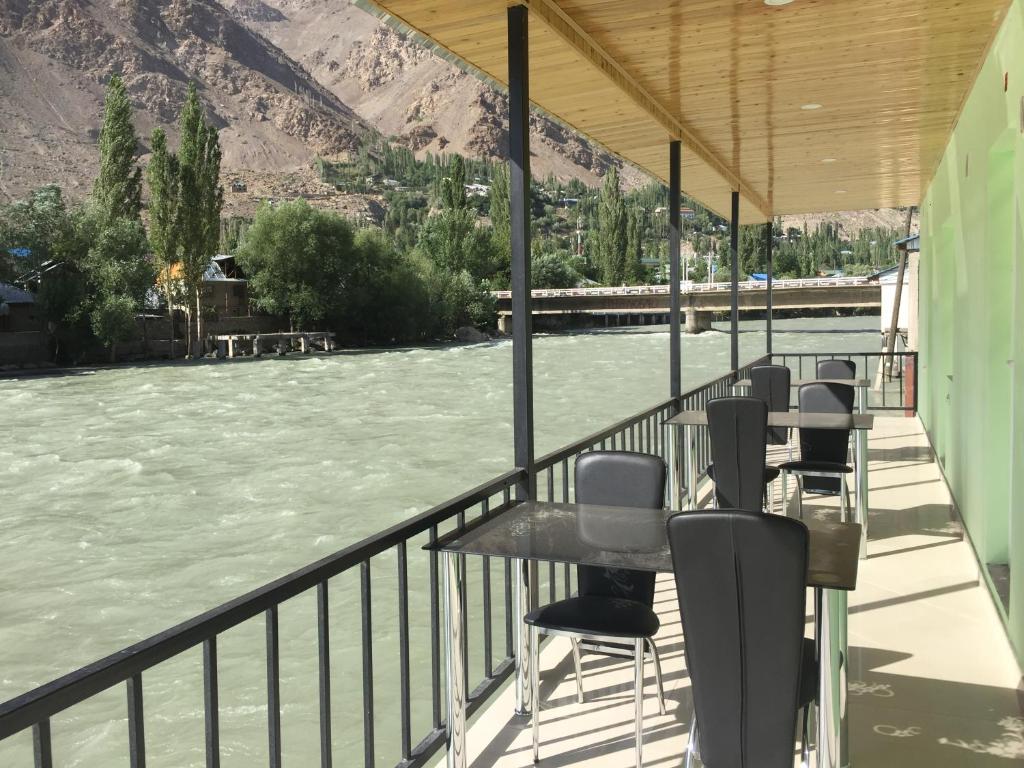 KhorogZarya Hotel的坐在河边阳台的一排椅子
