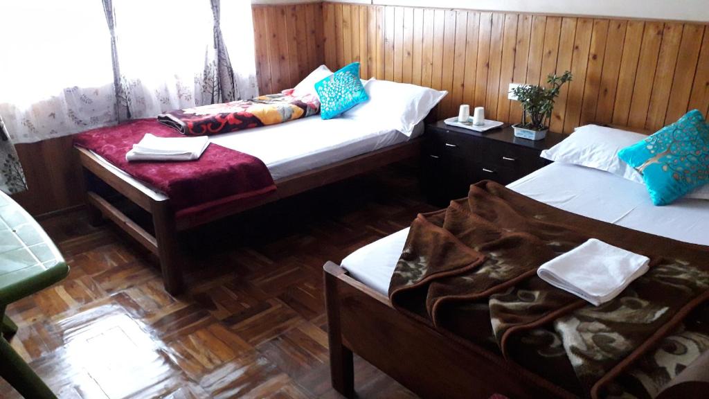 大吉岭White Tara home stay的配有木墙和木地板的客房中的两张床