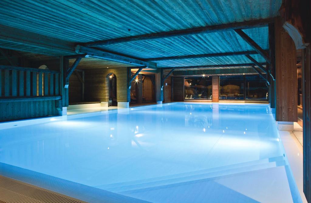 莱热Chalet-Hôtel La Marmotte, La Tapiaz & SPA, The Originals Relais (Hotel-Chalet de Tradition)的一座拥有蓝色天花板的大型游泳池