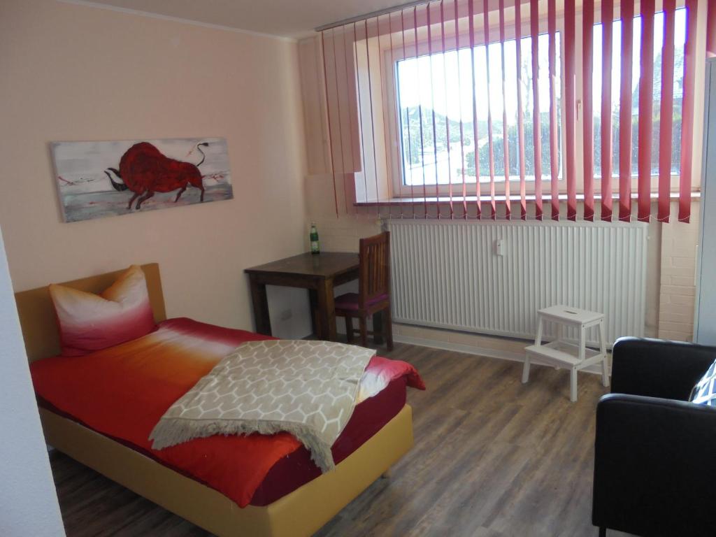 SchmalfeldHolstenhof"garni"的一间卧室配有一张床、一张桌子和一个窗户。