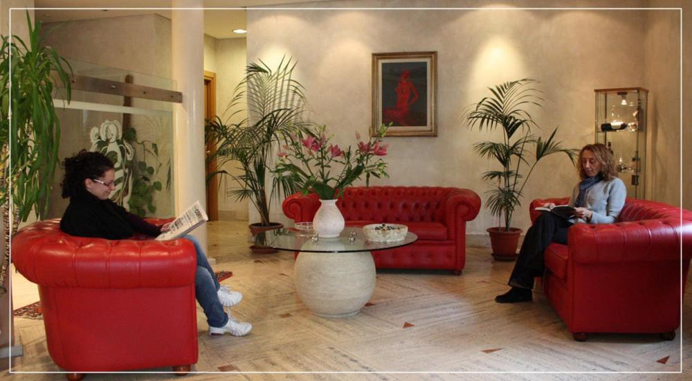 博恩孔文托希贝利诺酒店的两个女人坐在客厅的红色沙发上