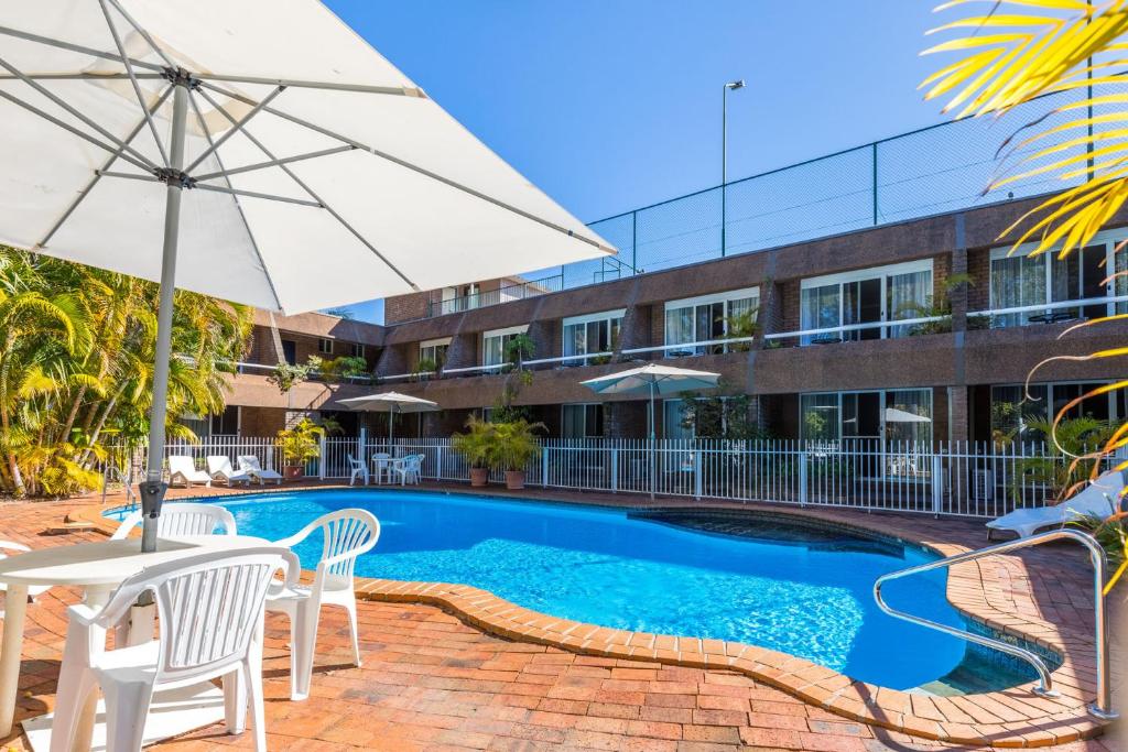科夫斯港阿曲亚吉汽车旅馆的一座带椅子和遮阳伞的游泳池以及一座建筑