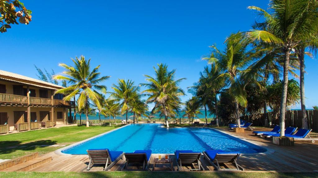 伊塔齐米林Pousada Praia das Ondas - Pé na areia的一个带椅子和棕榈树的大型游泳池