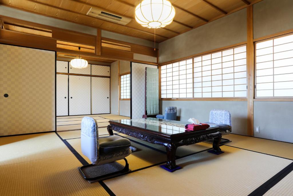 京都Konuka Yakushi Temple House的一间设有玻璃桌和两把椅子的房间
