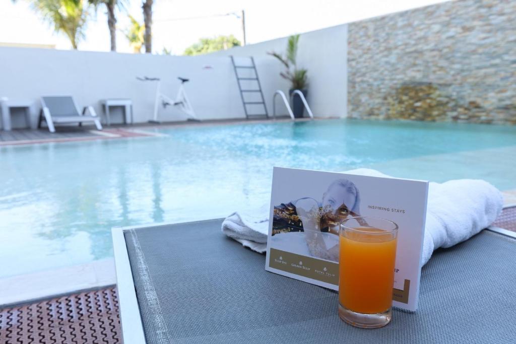 圣丹尼斯郁金香圣克洛蒂尔德酒店的坐在游泳池畔的桌子上喝一杯橙汁