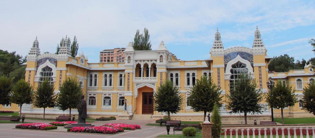 基兹洛沃茨克Санаторий Главные Нарзанные Ванны的一座黄色的大建筑,前面有鲜花