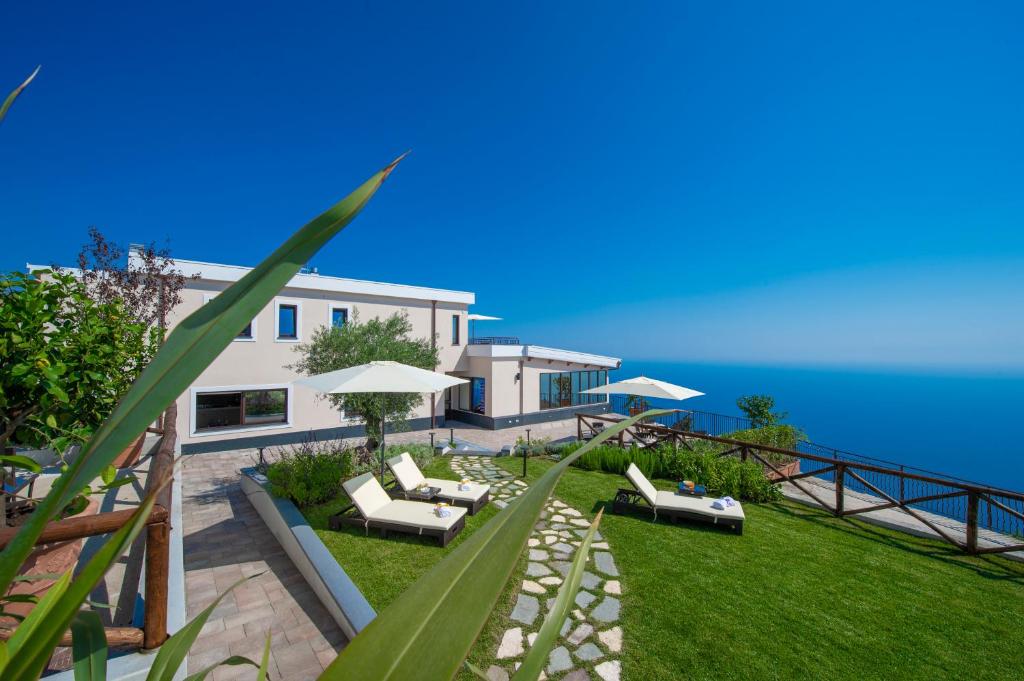 阿杰罗拉Villa Paradise Resort的一座带草坪、椅子和遮阳伞的房子