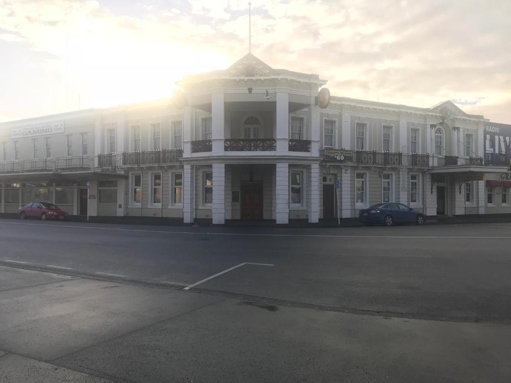 旺阿雷Grand Hotel - Whangarei的街道上一座大型白色建筑,设有阳台
