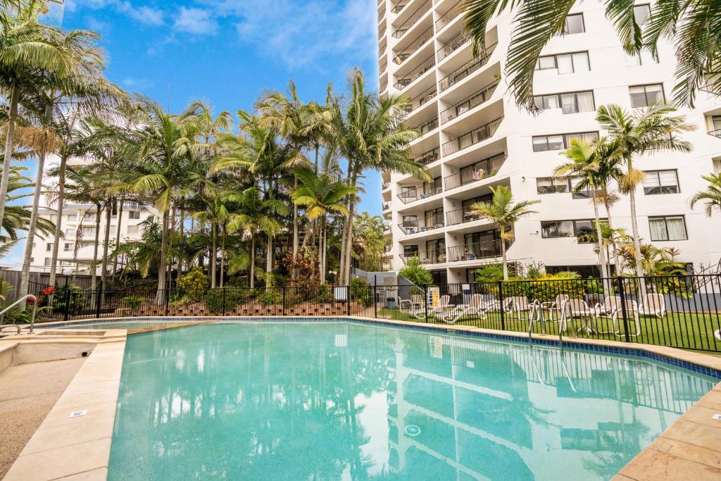 黄金海岸Horizons Holiday Apartments - OFFICIAL的一座楼前棕榈树游泳池