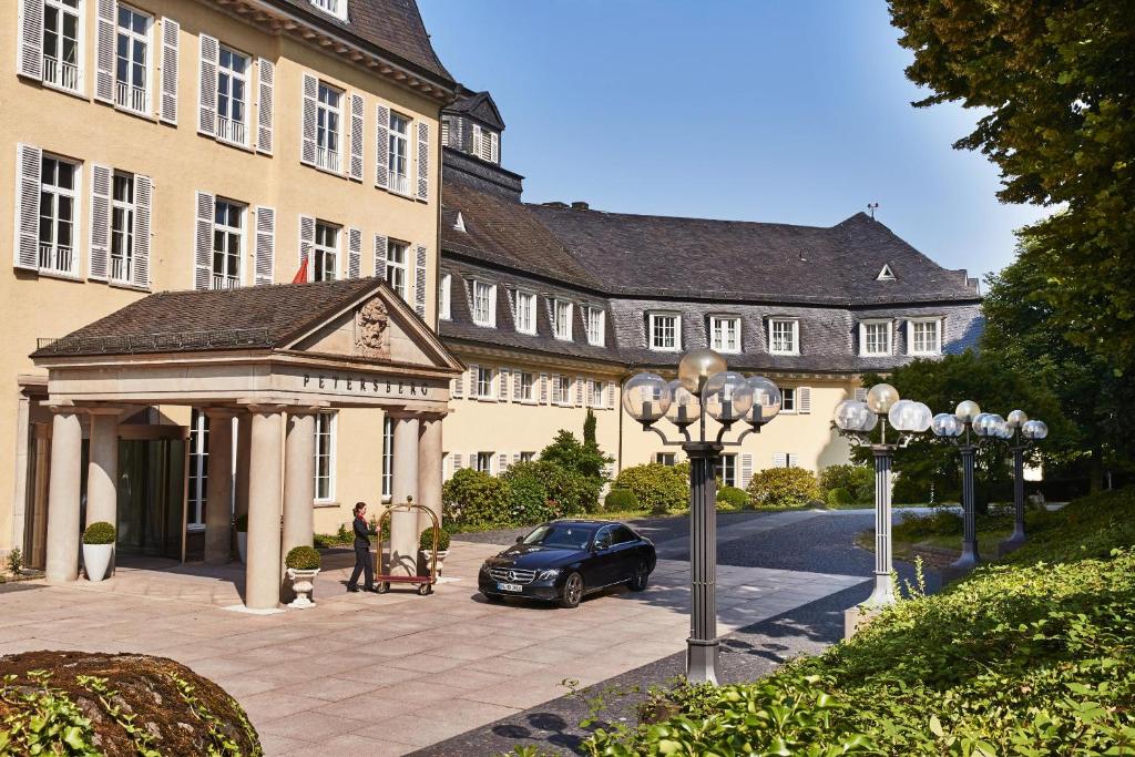 柯尼希斯温特Steigenberger Grandhotel & Spa Petersberg的停泊在带凉亭的大楼前的汽车