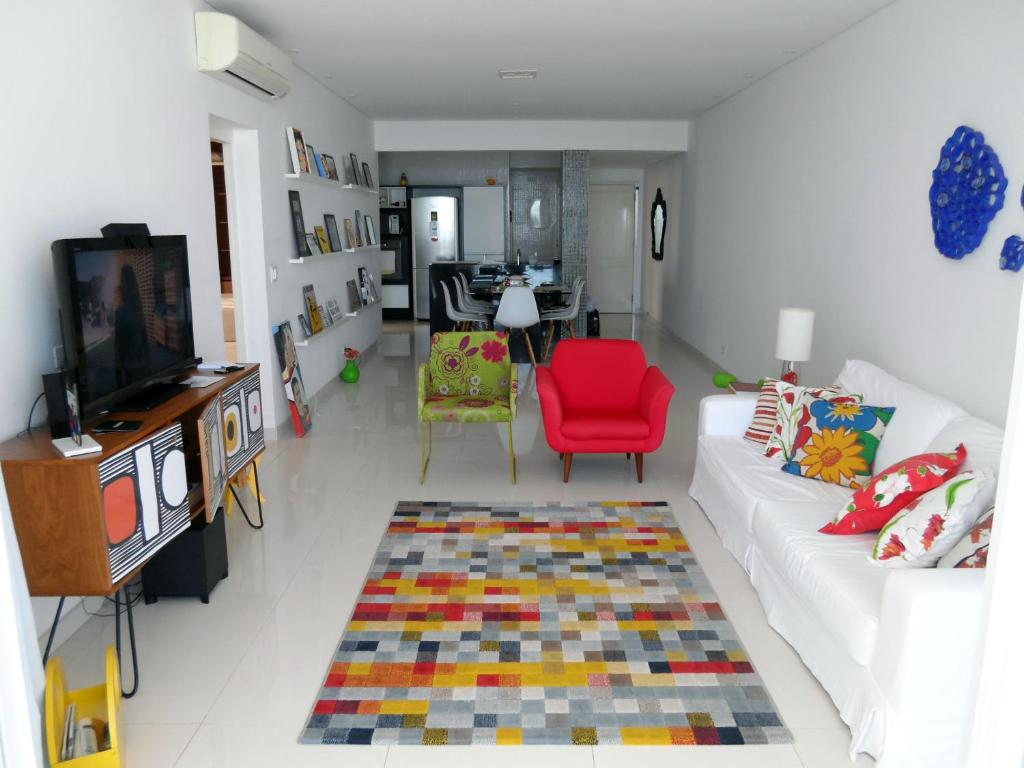 瓜鲁雅Pitangueiras - Apto. Frente Mar的客厅配有白色沙发和红色椅子