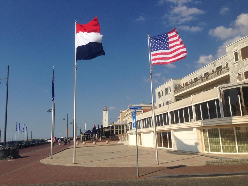 海滨诺德韦克Beach Rose, 1 free parking, 2 min. from beach, jacuzzi的两面旗帜在建筑物前面飞