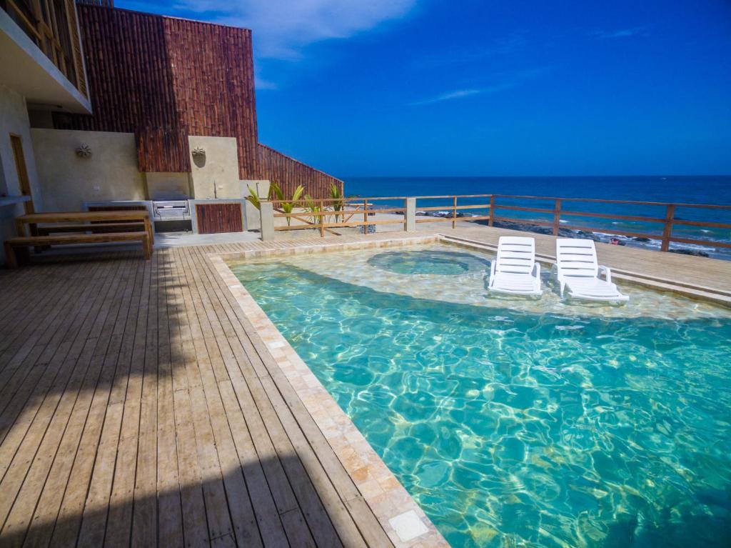 卡诺阿斯德蓬萨尔Canoas Lofts的一个带两把椅子的游泳池以及大海