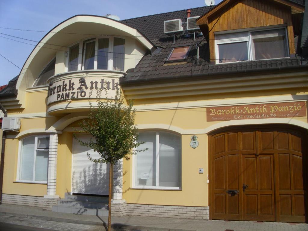 凯奇凯梅特Barokk Antik Guest Hause的一座大型黄色建筑,设有木制车库