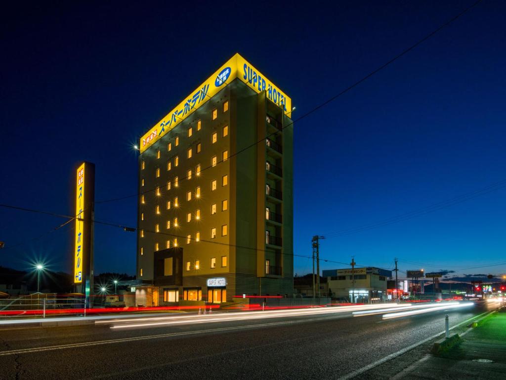磐城Super Hotel Fukushima Iwaki的一座酒店大楼,上面有 ⁇ 虹灯标志