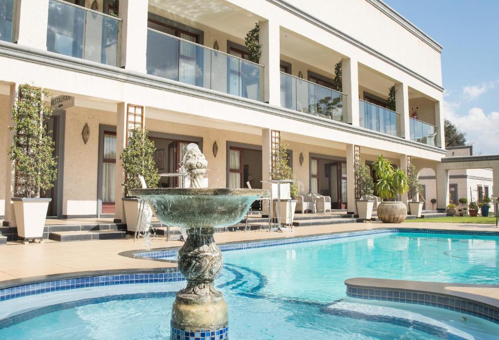 约翰内斯堡栀子花精品酒店的一座大楼前的游泳池,带喷泉
