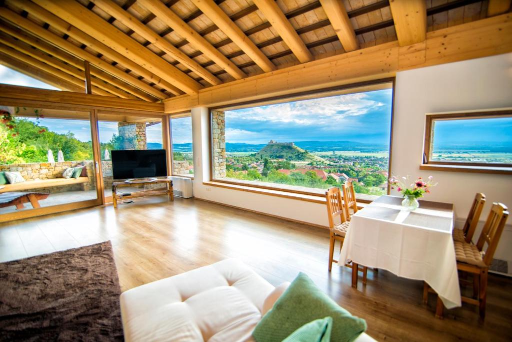 许迈格Villa Terazza-Panorama Apartman的客厅配有桌椅和大窗户