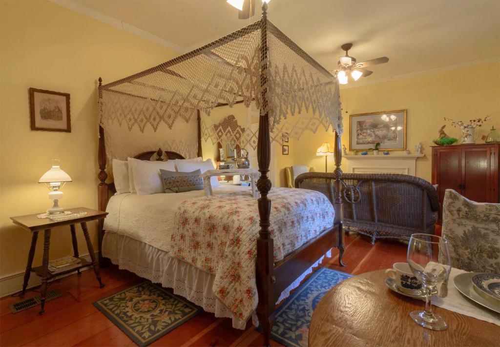 纳奇兹Magnolia Cottage Bed and Breakfast的一间卧室配有一张天蓬床和一张桌子