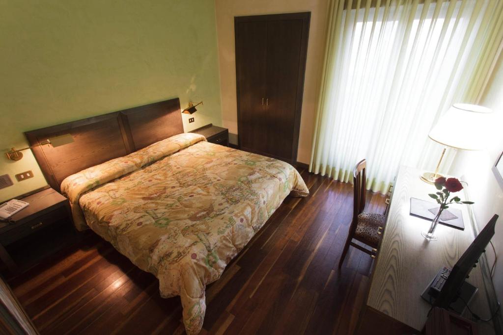 弗罗西诺内Astor Hotel Vintage的一间卧室配有一张床、一张桌子和一盏灯