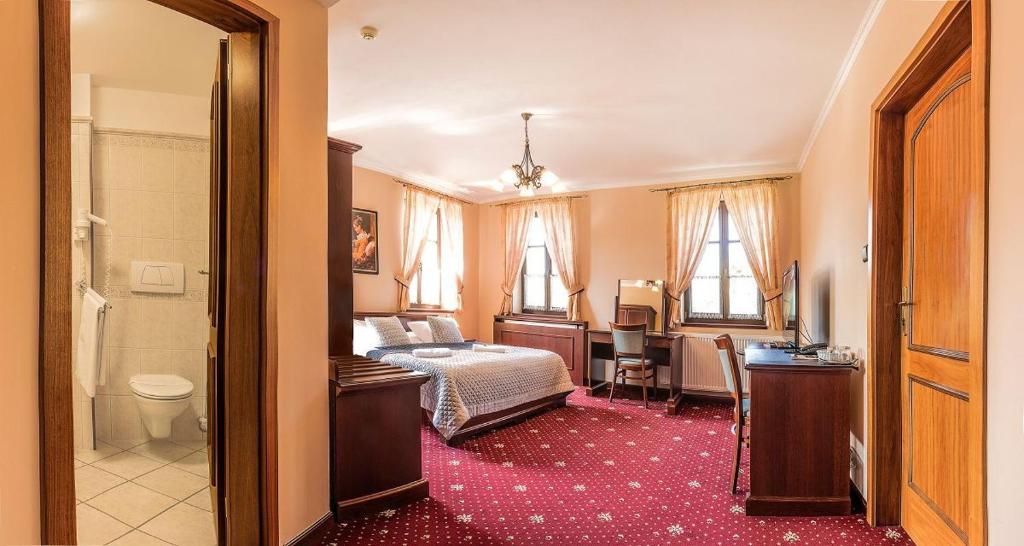 布赫洛维采巴克罗维斯酒店的一间带一张床和一张书桌的卧室以及一间浴室。