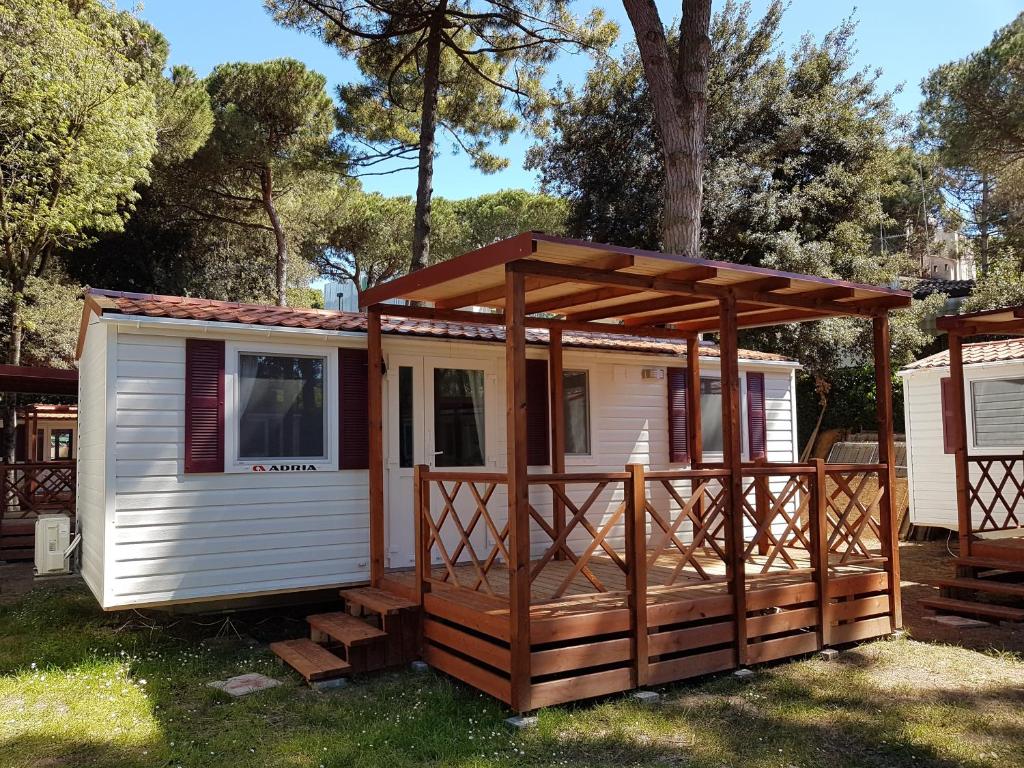 丽都斯皮纳Victoria Mobilehome in Camping Mare e Pineta的一个小房子,设有门廊和甲板