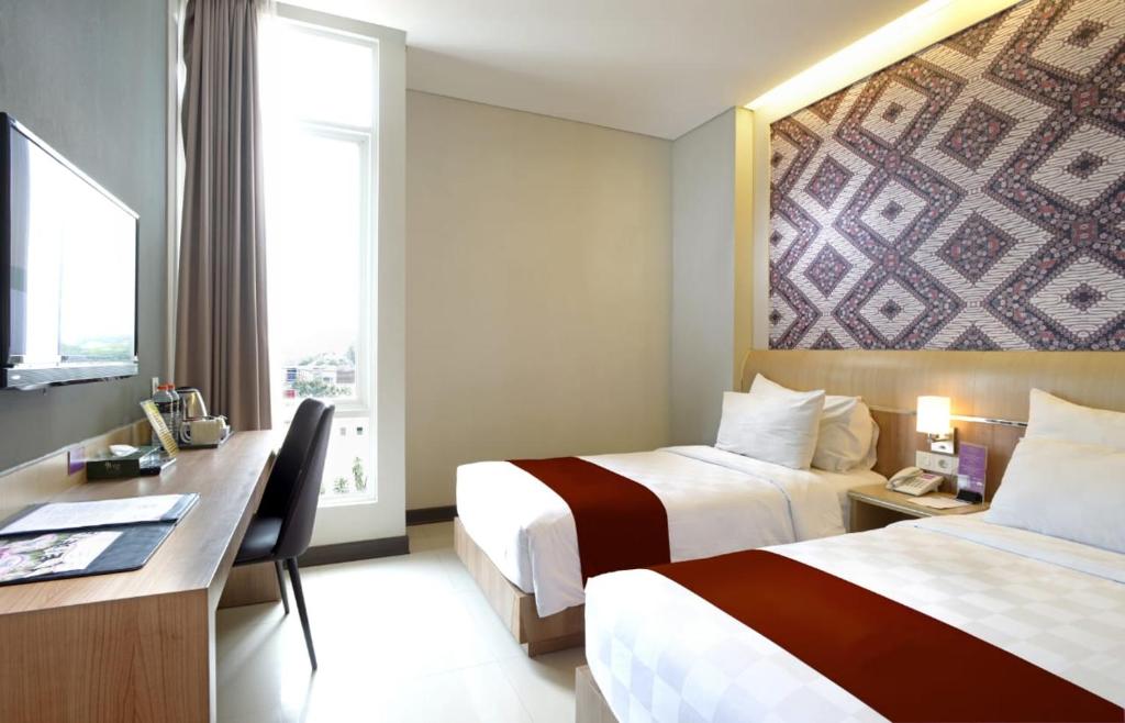 日惹D'Kalpa Hotel Demangan Yogyakarta的酒店客房配有两张床和一张书桌