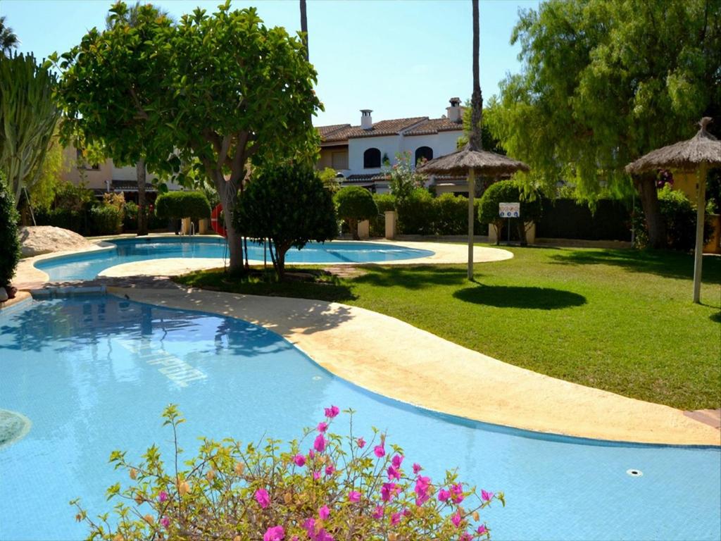 哈维亚Casa Arenal的一座种有树木和鲜花的庭院内的游泳池