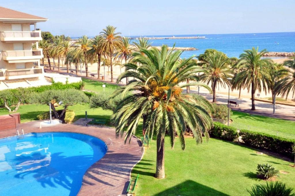坎布里尔斯Magica Planet Costa Dorada的拥有游泳池、棕榈树和海滩的度假酒店
