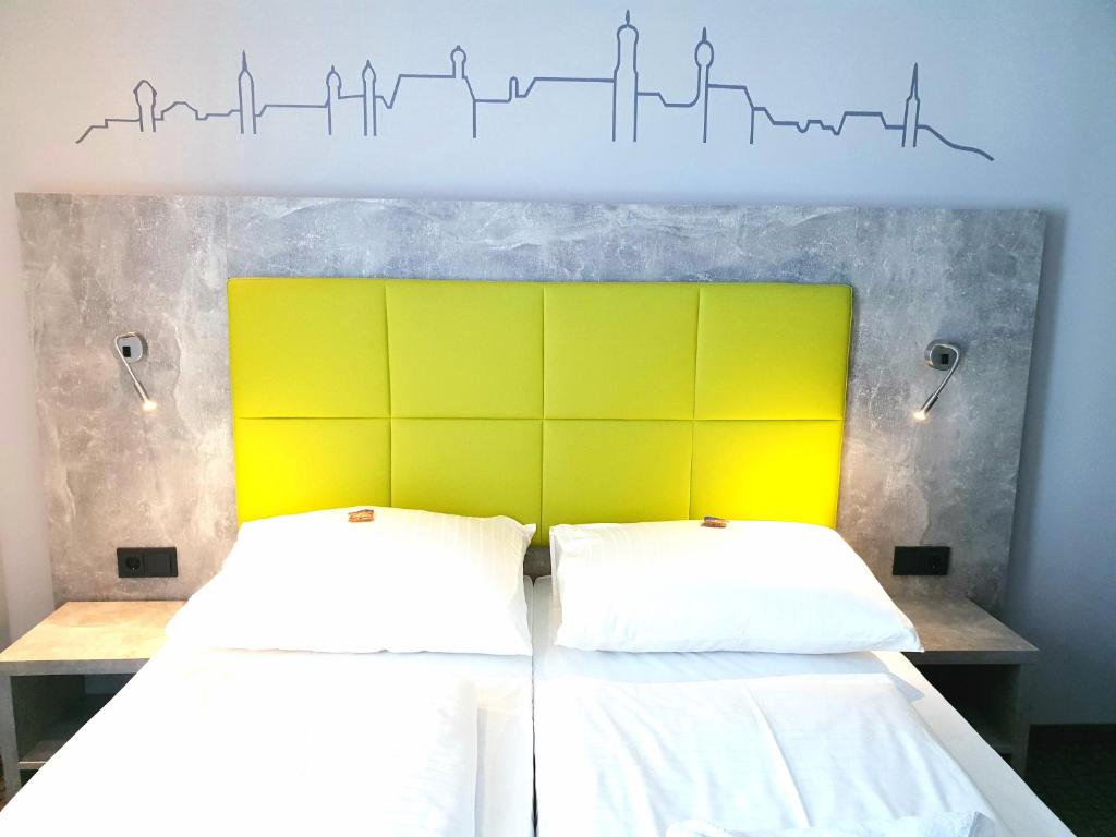 多瑙河畔迪林根SleepySleepy Hotel Dillingen的一间卧室设有两张带黄色床头板的床