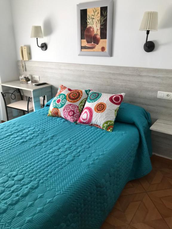 卡塞雷斯阿真蒂纳旅馆的一间卧室配有一张带蓝色床单和枕头的床。