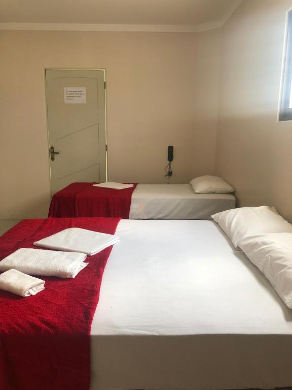 卡鲁阿鲁Prime Hotel的配有红色毯子和白色床单的客房内的两张床