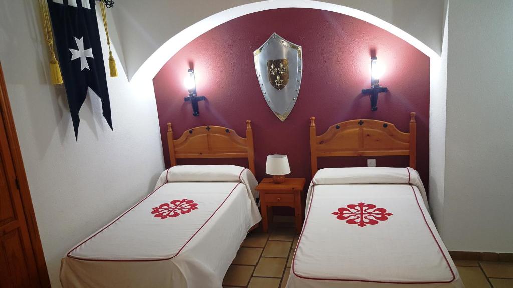 La Calzada de Calatrava奥斯培德里亚酒店的两张床位于带两盏灯的墙上。