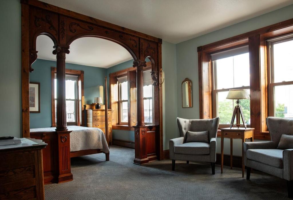 斯特金贝Inn at Cedar Crossing的一间卧室配有一张床、一把椅子和镜子