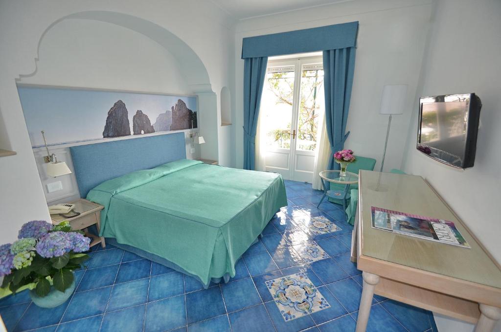 卡普里阿尔贝格加托比昂科酒店的一间卧室设有一张绿色的床和一个窗户。