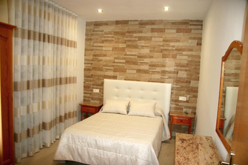 波索阿尔孔Hostal Restaurante Grela的一间卧室设有一张床和砖墙