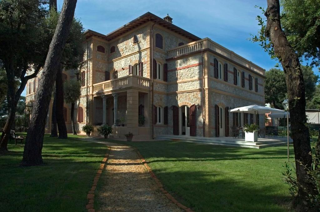 马里纳-迪-皮特拉桑塔西格诺里别墅酒店的一座大型石头建筑,前面有树木