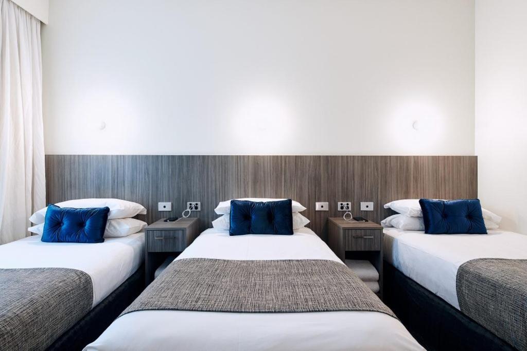 拉弗顿拉弗顿俱乐部酒店的两张位于酒店客房的床,配有蓝色枕头