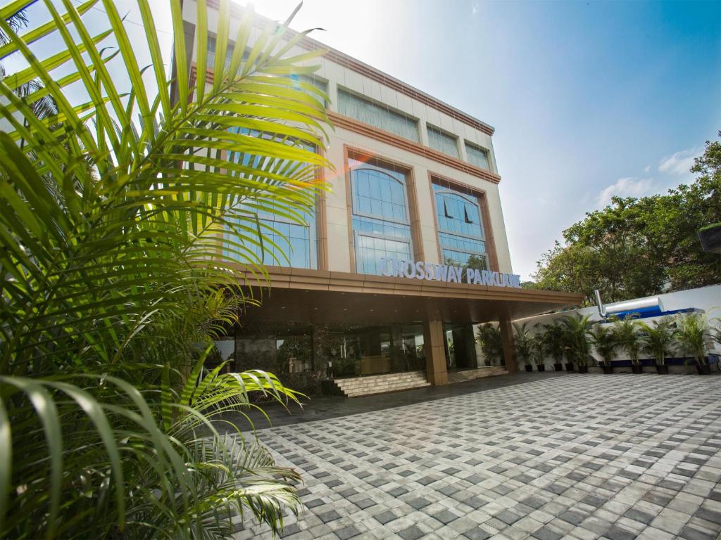 钦奈ST Parklane Airport Hotel Chennai的前面有棕榈树的建筑