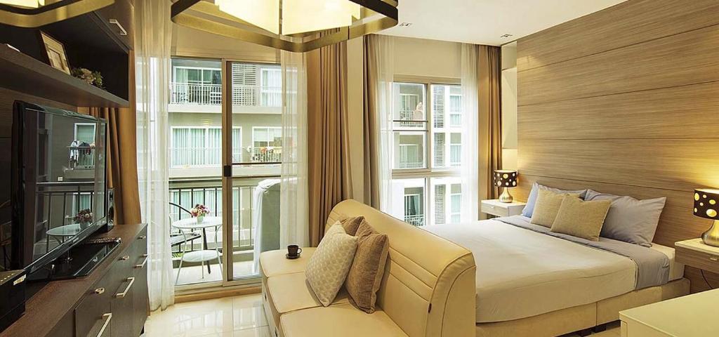 乔木提恩海滩画廊乔木提恩海滩芭堤雅精品公寓的一间卧室配有一张床、一张沙发和窗户。