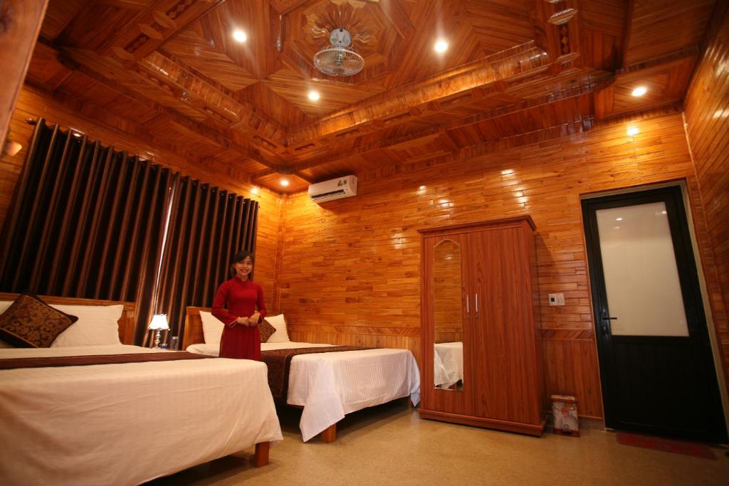 峰牙Sky Hotel的一位妇女站在带两张床的房间