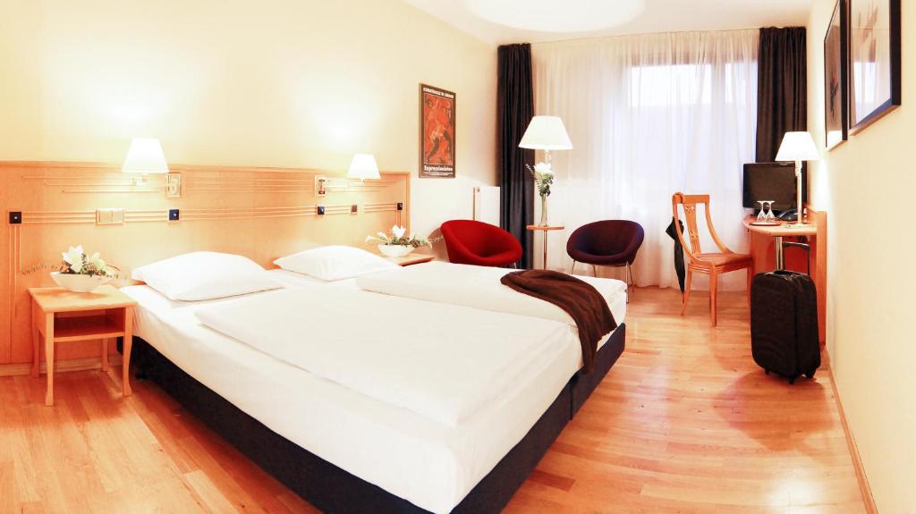 什未林Boulevard Hotel Altstadt Schwerin的酒店客房带大型白色床和椅子