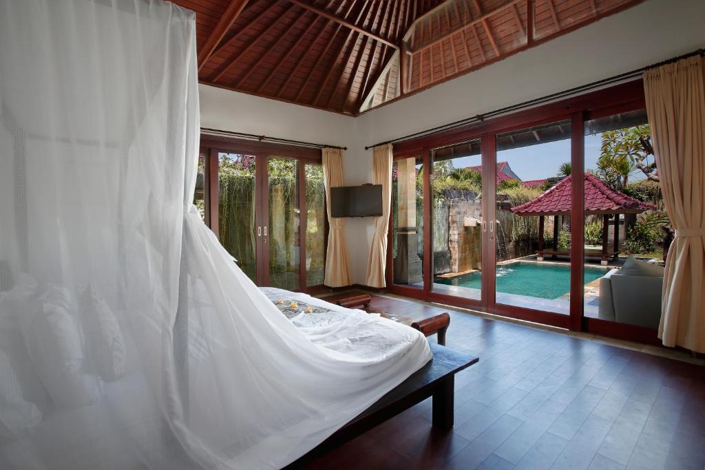 塞米亚克总理酒店集团巴厘岛总理别墅的一间带白色床的卧室和一个游泳池
