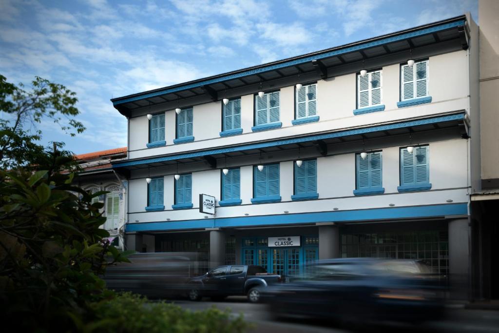 新加坡Hotel Classic by Venue的一辆汽车驶过蓝色百叶窗的建筑